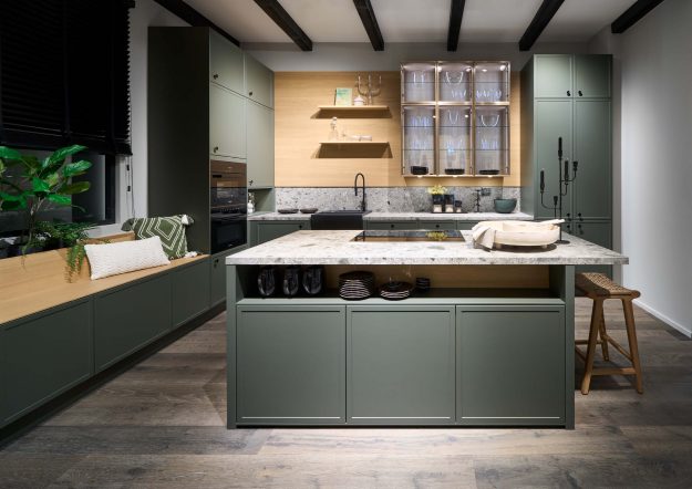 Moderne Landhausküche von Häcker mit grünen Fronten und Kochinsel erhältlich bei Das Küchenstudio